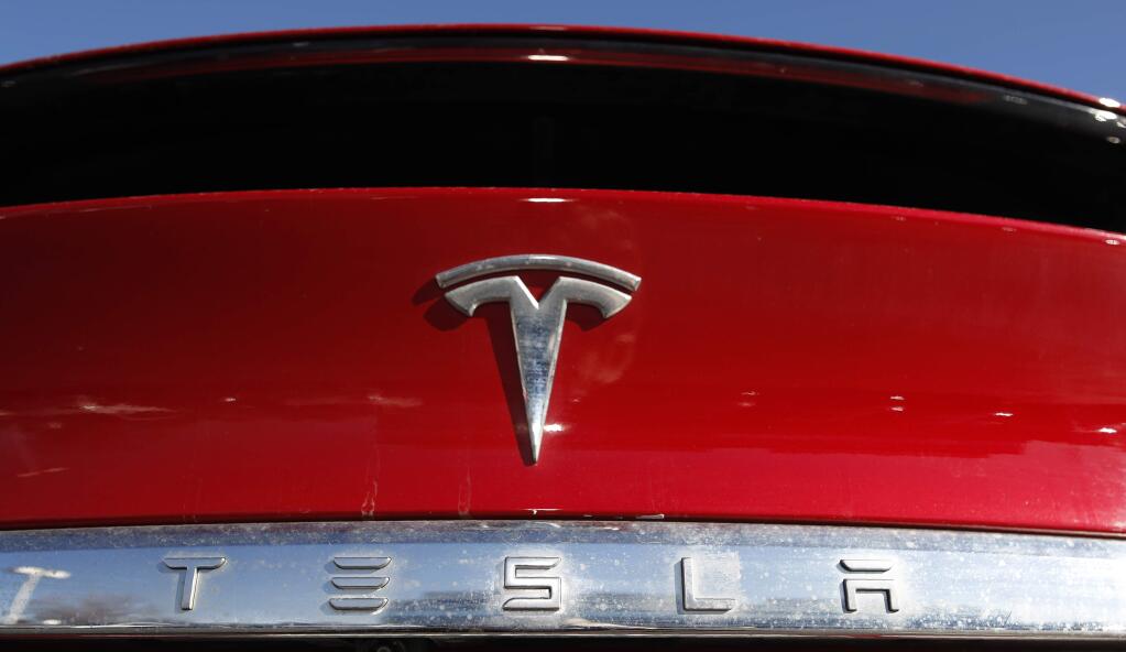 FILE - In this Feb. 2, 2020 file photograph, the company logo sits on an unsold 2020 Model X at a Tesla dealership in Littleton, Colo. Shares of Tesla Inc. fell 4% in early trading Thursday, Feb. 13, after the electric vehicle and solar panel maker said it would sell more than $2 billion worth of additional shares. The move comes just two weeks after CEO Elon Musk said the company had enough cash to fund its capital programs and it didn't need to raise any more money. (AP Photo/David Zalubowski, File)