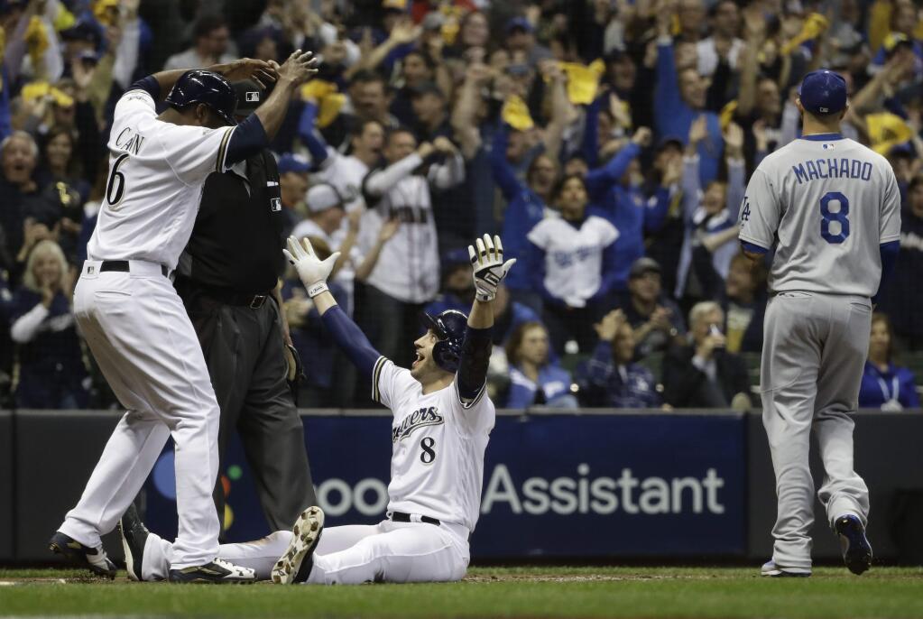 The Milwaukee Brewers' Ryan Braun celebrates with Lorenzo Cain after scoring on a double by Jesus Aguilar during the first inning of Game 6 of the National League Championship Series against the Los Angeles Dodgers Friday, Oct. 19, 2018, in Milwaukee. (AP Photo/Matt Slocum)
