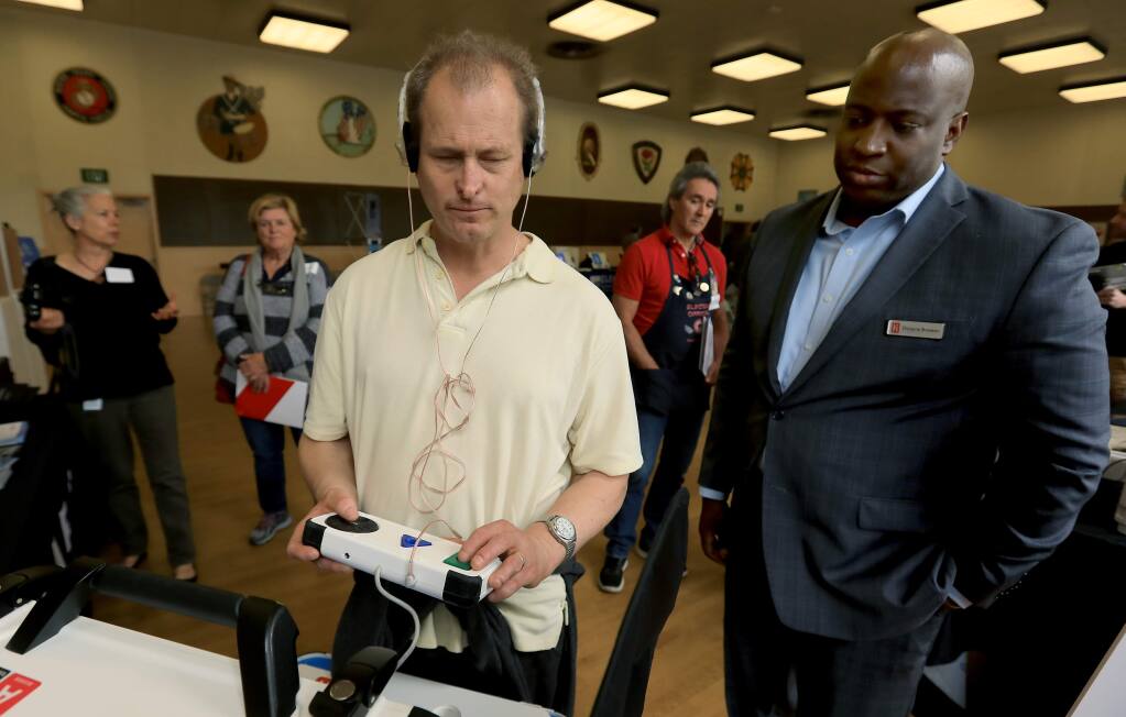 Earl Baum Center's Director of Facilities and Technology Jeff Harrington gives a voting machine from Hart InterCivic of Austin, Thursday April 12, 2018 during a demonstration of new age voting technology by various companies at the Santa Rosa Veterans Hall. At right is Hart representative Dwayne Broxton. (Kent Porter / The Press Democrat) 2018