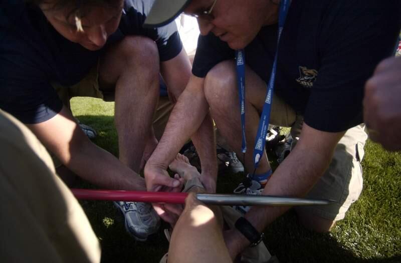 Medical personnel stabilize Ogden Standard-Examiner photographer Ryan McGeeney's leg after he was pierced by a javelin directly below his right knee while covering the Utah state high school track championships at Brigham Young University's Clarence Robison track stadium in Provo, Utah. McGeeney was transported by ambulence to Utah Valley Regional Medical Center, where the javelin was removed. He received 13 stitches, but suffered no serious damage to any ligaments or tendons. McGeeney took the photo himself. (AP Photo/Ryan McGeeney)