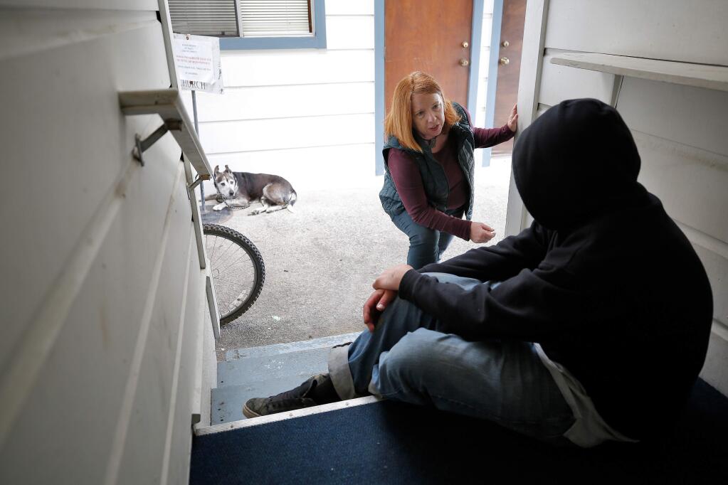Behavioral health clinician Charmaine Rable of the Sonoma County Department of Health Services talks with Jeremiah White, who has been homeless off and on for four years, as he rests in an alcove at St. Paul's Episcopal Church in Healdsburg, California, on Thursday, March 21, 2019. (Alvin Jornada / The Press Democrat)