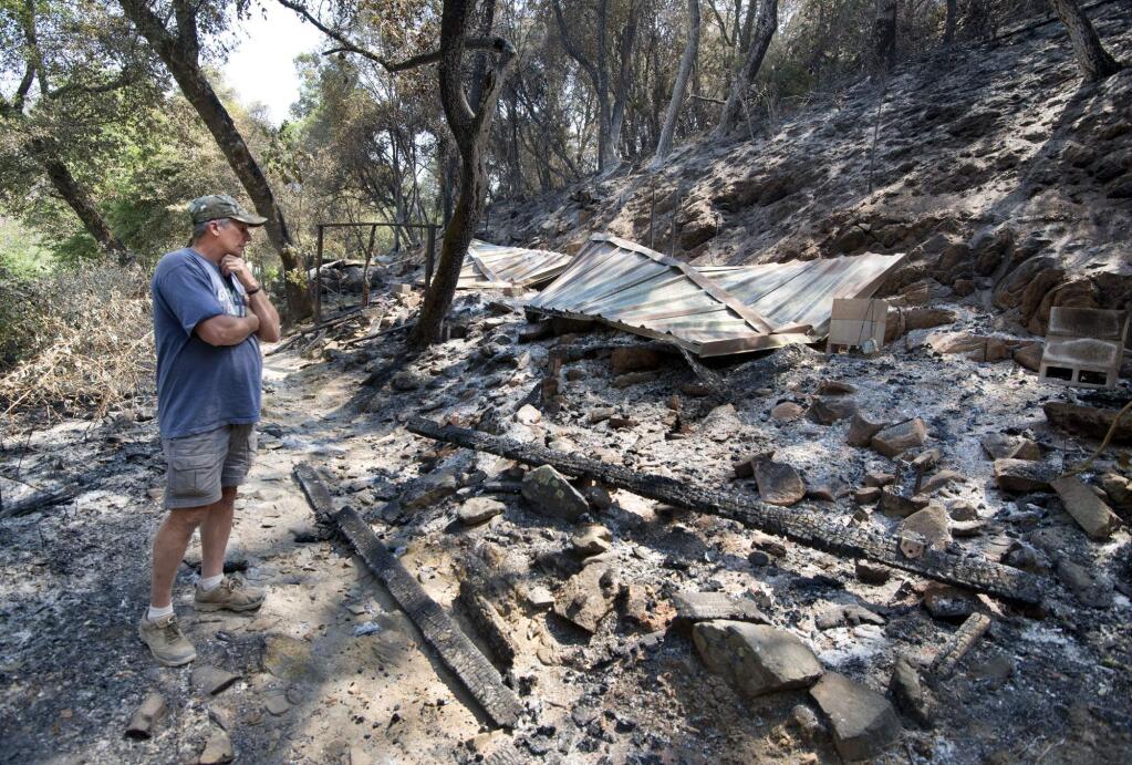 Bill Cleek looks over the remains of one of his cabins which was destroyed by a fire at his Rancho Cicada Retreat in Amador County, Sunday, July 27, 2014, in Plymouth, Calif. Firefighters in Northern California on Sunday battled a wildfire that has destroyed 10 homes and forced hundreds of evacuations in the Sierra Nevada foothills, while a fire near Yosemite National Park destroyed one home and grew significantly overnight. (AP Photo/The Sacramento Bee, Randy Pench)