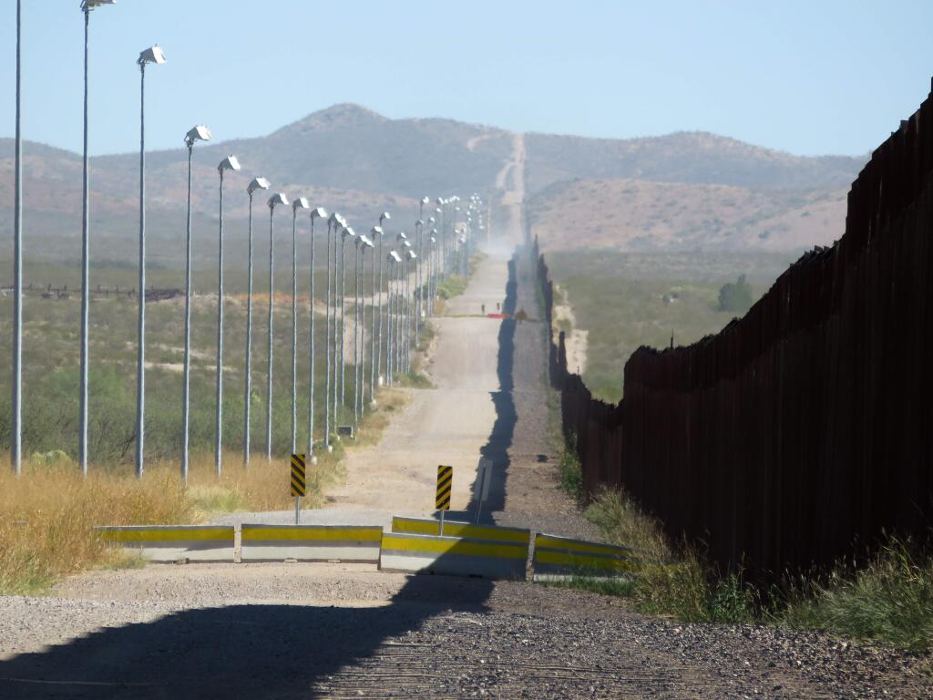 In this Nov. 15, 2016, photo provided by Kenneth Madsen, stadium lights atop tall poles oversee a pedestrian barrier stretching for miles along a section of the border wall between Douglas, Arizona, and Agua Prieta, in the Mexican state of Sonora. A new photo exhibit by Madsen opening Wednesday, Sept. 19, 2018, at the Ohio State University-Newark campus, 'Up Close with U.S.-Mexico Border Barriers,” highlights different types of border wall fencing. (Kenneth Madsen via AP)