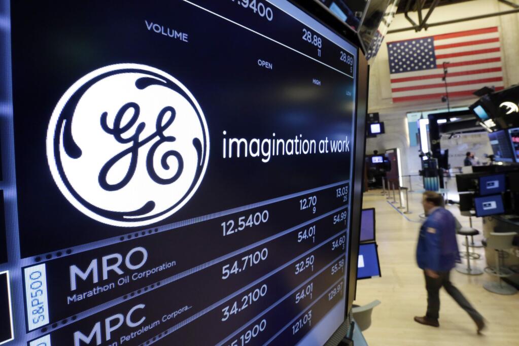 FILE - In this Monday, June 12, 2017, file photo, the General Electric logo appears above a trading post on the floor of the New York Stock Exchange. GE said Monday, Nov. 13, 2017, that it is slashing its quarterly dividend in half with investors gathering in Boston, where Chairman and CEO John Flannery is expected to lay out significant changes for the U.S. company. (AP Photo/Richard Drew, File)