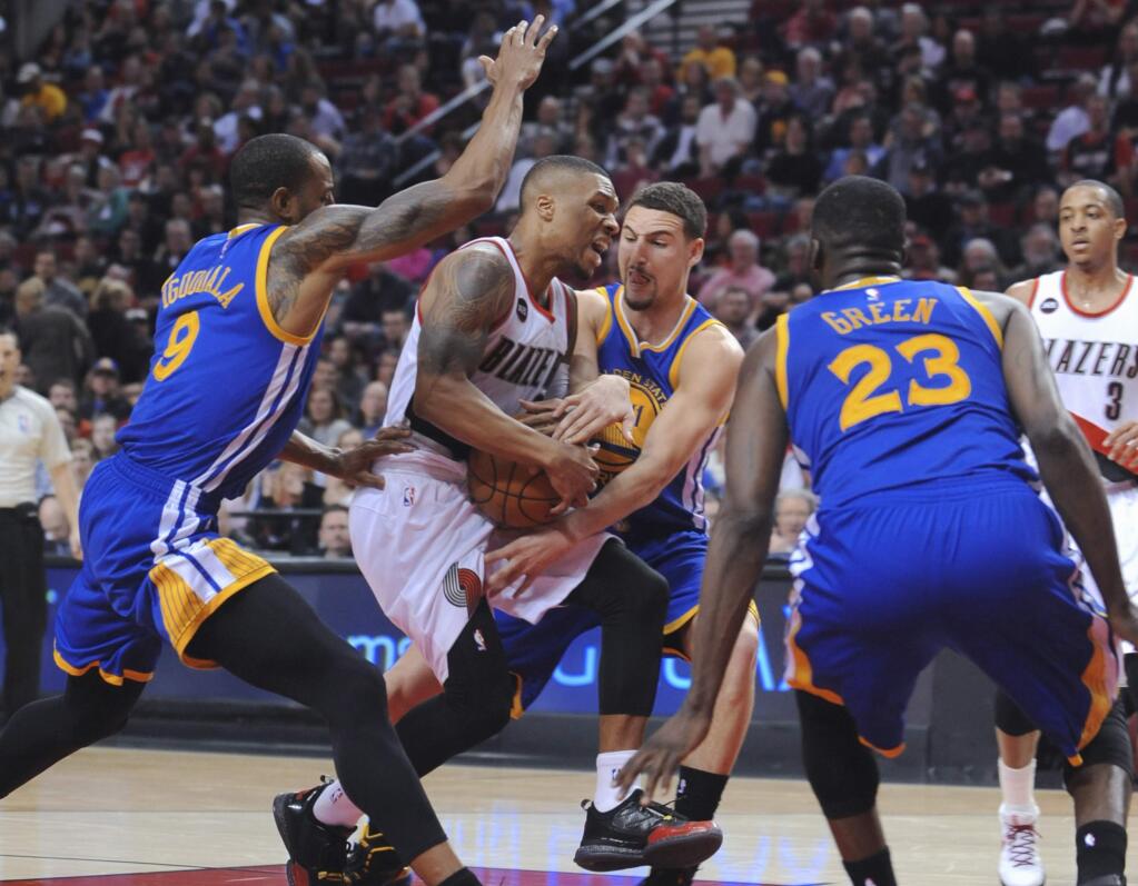 Portland Trail Blazers' Damian Lillard (0) is tied up under the basket by Golden State Warriors' Andre Iguodala (9), Klay Thompson (11) and Draymond Green (23) during the second half of an NBA basketball game in Portland, Ore., Tuesday, March 24, 2015. The Warriors won 122-108. (AP Photo/Greg Wahl-Stephens)