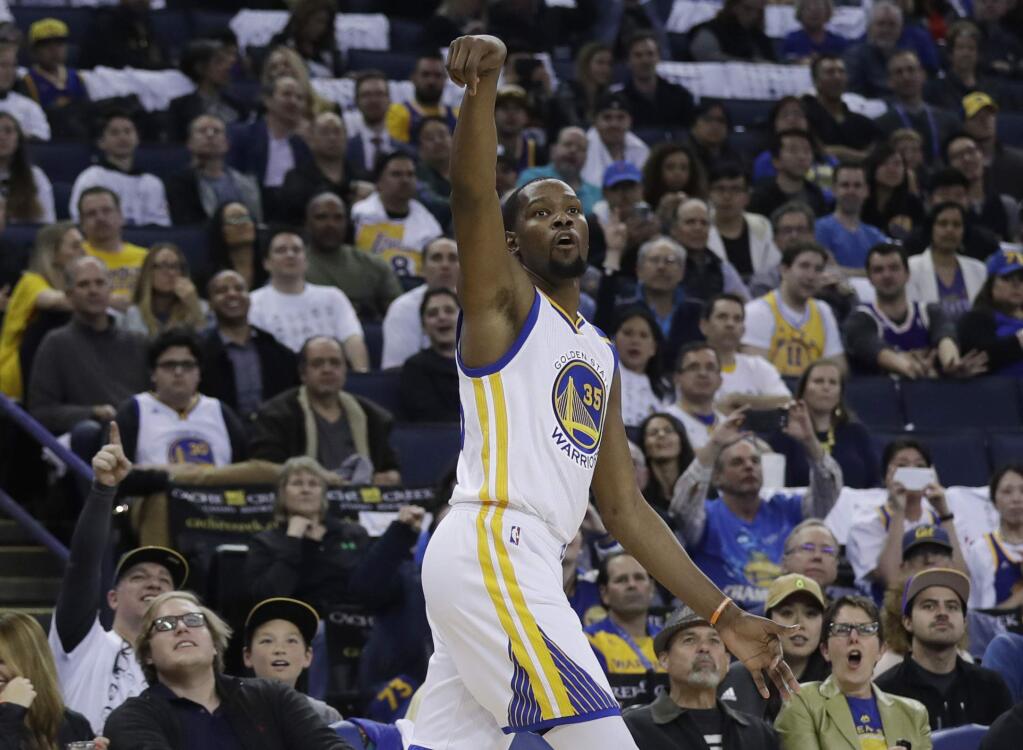 The Golden State Warriors' Kevin Durant follows through on a 3-point basket during the second half against the Los Angeles Lakers on Wednesday in Oakland. (AP Photo/Marcio Jose Sanchez)