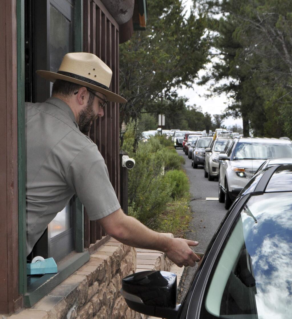 FILE - In this Aug. 2, 2015, file photo, Nate Powell, an employee with Grand Canyon National Park, collects an entrance fee an entrance gate at Grand Canyon National Park, Ariz. (Emery Cowan/Arizona Daily Sun via AP, File)