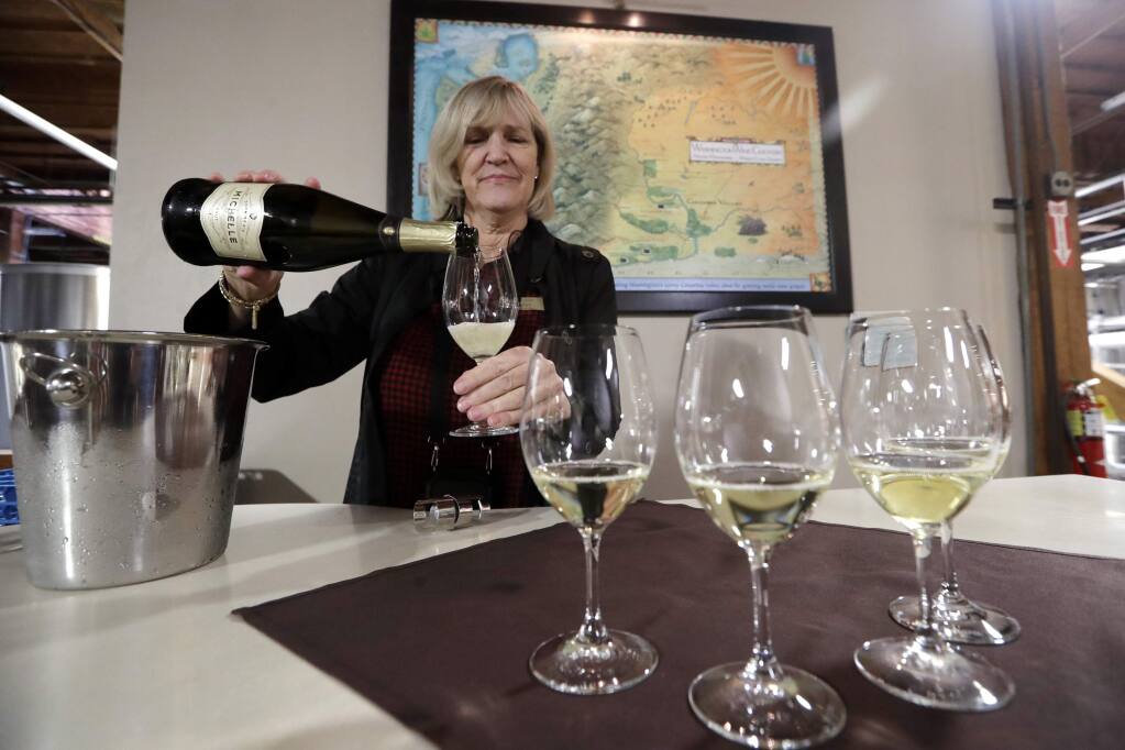 Guest services representative Ginny Swanstrom pours a sparkling wine for a tour group to taste at Chateau Ste. Michelle winery in Woodinville, Washington in 2019. Sparkling wine continues to outpace most other categories in shipment growth, according to Nielsen IQ. (AP Photo/Elaine Thompson)
