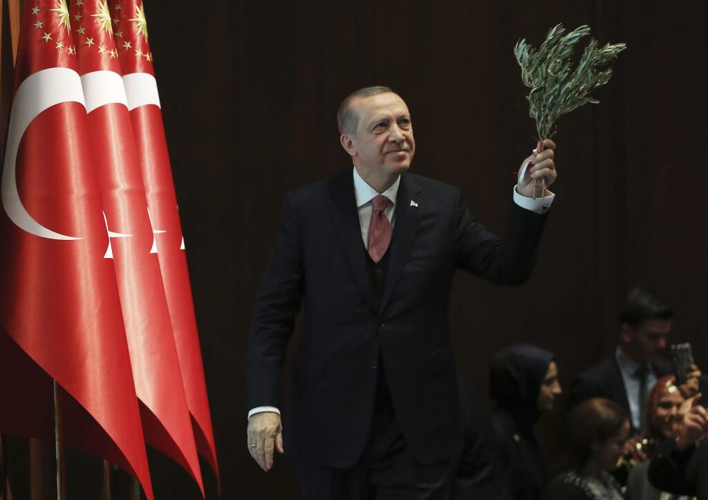 Turkey's President Recep Tayyip Erdogan, holding an olive branch arrives to deliver a speech at an event in Ankara, Turkey, Tuesday, Feb. 20, 2018. Erdogan said Turkish troops involved in the month-long offensive, codenamed 'Operation Olive Branch', to drive out Syrian Kurdish militiamen from a northwestern Syrian enclave will soon begin a siege of the city of Afrin. (Pool Photo via AP)