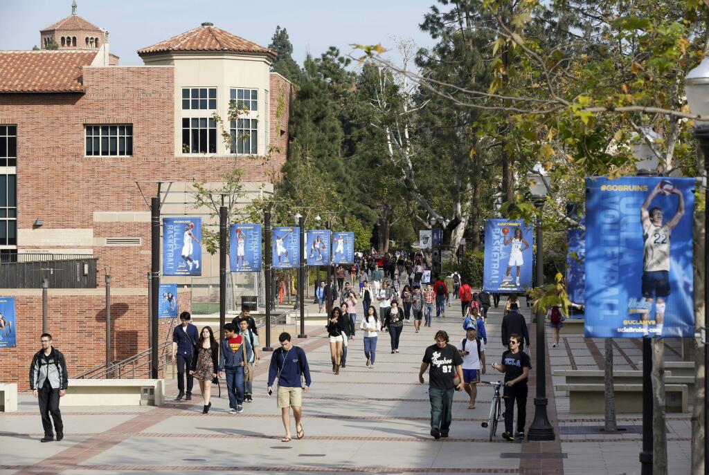 FILE - In this Feb. 26, 2015, file photo, students walk on the University of California, Los Angeles campus. Federal authorities have charged college coaches and others in a sweeping admissions bribery case in federal court. The racketeering conspiracy charges were unsealed Tuesday, March 12, 2019, against coaches at schools including UCLA, Wake Forest, Stanford, Georgetown, and the University of Southern California. (AP Photo/Damian Dovarganes, File)
