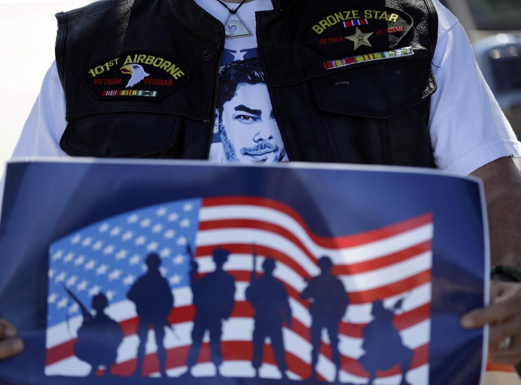 Danny Jackson, Vietnam War veteran and supporter of Democratic congressional candidate Ammar Campa-Najjar, wears a shirt with a likeness of the candidate as he holds a sign during a news conference Tuesday, Oct. 16, 2018, in San Diego. Campa-Najjar faces indicted U.S. Rep. Duncan Hunter in the race for Southern California's 50th district. Hunter is stepping up efforts to convince voters his Democratic opponent is a security threat because of his family's background - something the Latino, Arab-American businessman forcefully rejects as a desperate attempt by an incumbent under indictment. (AP Photo/Gregory Bull)