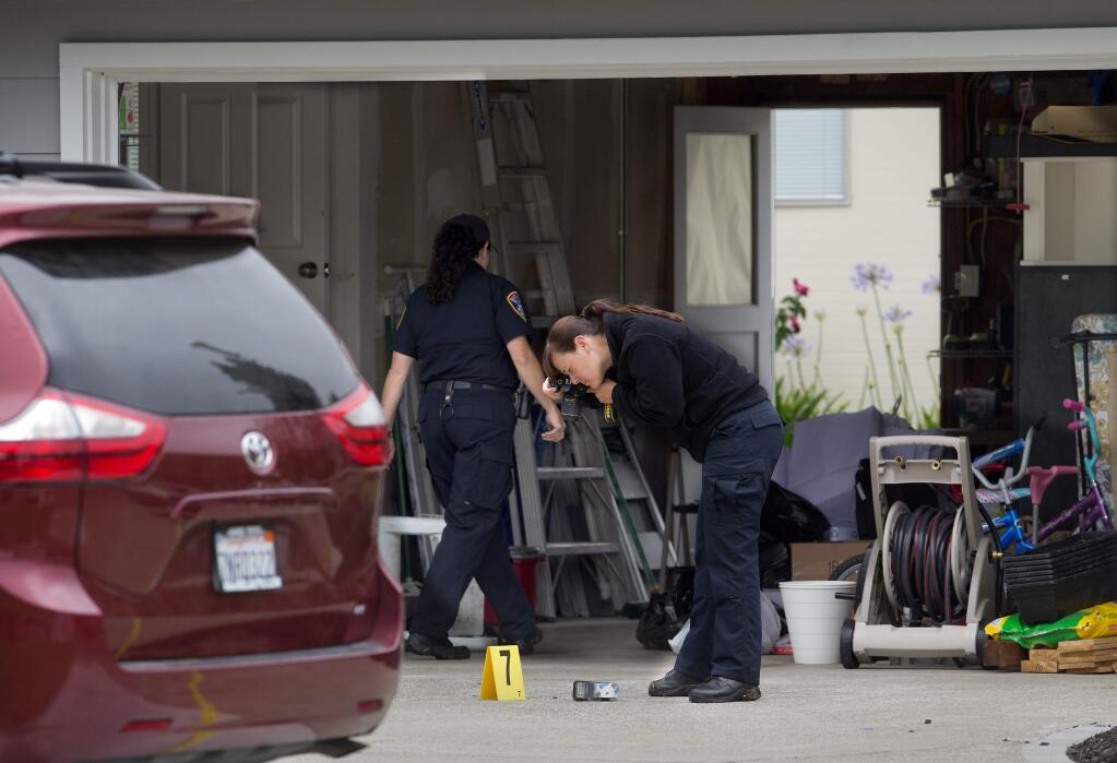 Santa Rosa police crime scene investigators photograph a roll of packing tape marked as evidence at the scene of a homicide on Garfield Park Ave. in Santa Rosa. (photo by John Burgess/The Press Democrat)