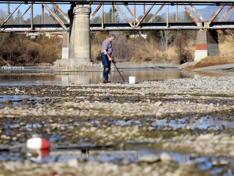 File - In this Jan. 14, 2014 file photo, Hugh Beggs of Santa Rosa, Calif., searches for coins in the middle of the Russian River at Healdsburg Veterans Memorial Beach in Healdsburg, Calif., taking advantage of the way below normal river flow. Seventeen rural communities in drought-stricken California are in danger of running out of water within four months, according to a list compiled by state officials. Wells are running dry or reservoirs are nearly empty in some communities. Others have long-running problems that predate the drought. The communities range from the area covered by the tiny Lompico County Water District in Santa Cruz County to the cities of Healdsburg and Cloverdale in Sonoma County. (AP Photo/ Santa Rosa Press Democrat, Kent Porter, File)