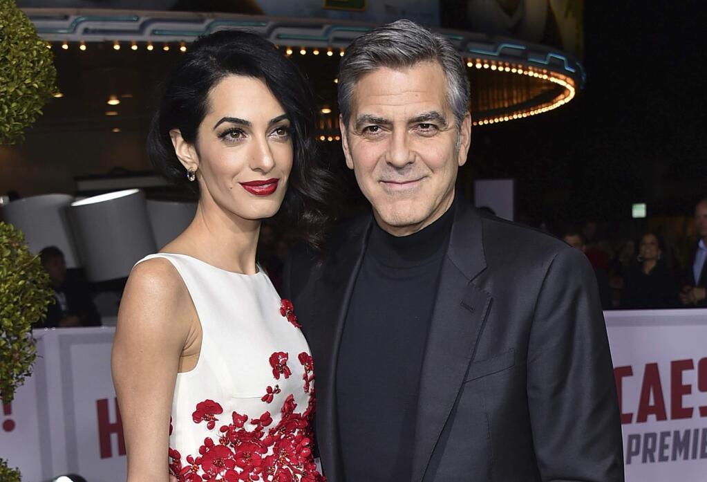 FILE - In this Feb. 1, 2016, file photo, Amal Clooney, left, and George Clooney arrive at the world premiere of 'Hail, Caesar!' in Los Angeles. The couple announced Tuesday, Aug. 22, 2017, that their Clooney Foundation for Justice is supporting the Southern Poverty Law Center with a $1 million grant to combat hate groups in the United States. (Photo by Jordan Strauss/Invision/AP, File)