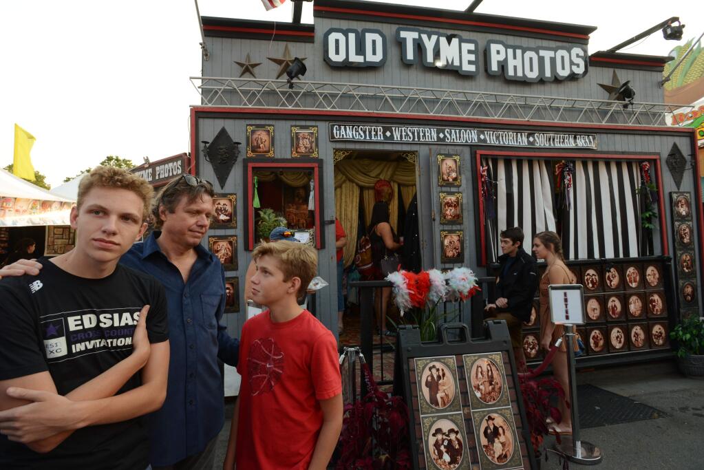 Doug Swanson with his sons Kaden Swanson, 15, left, and Shane Swanson, right waiting to take their family portrait at the Old Tyme Photos booth at the Sonoma County Fair in Santa Rosa, California. The Swansons having been taking family portraits at this booth every year since around 2003. A wall in their home displayed all their booth photos but were lost when the Swansons lost their Fountaingrove home to the October wildfires. Photo booth owner Amber Alexander-Greene has been trying to replace all their previous booth photos for free. August 9, 2018.(Photo: Erik Castro/for The Press Democrat)