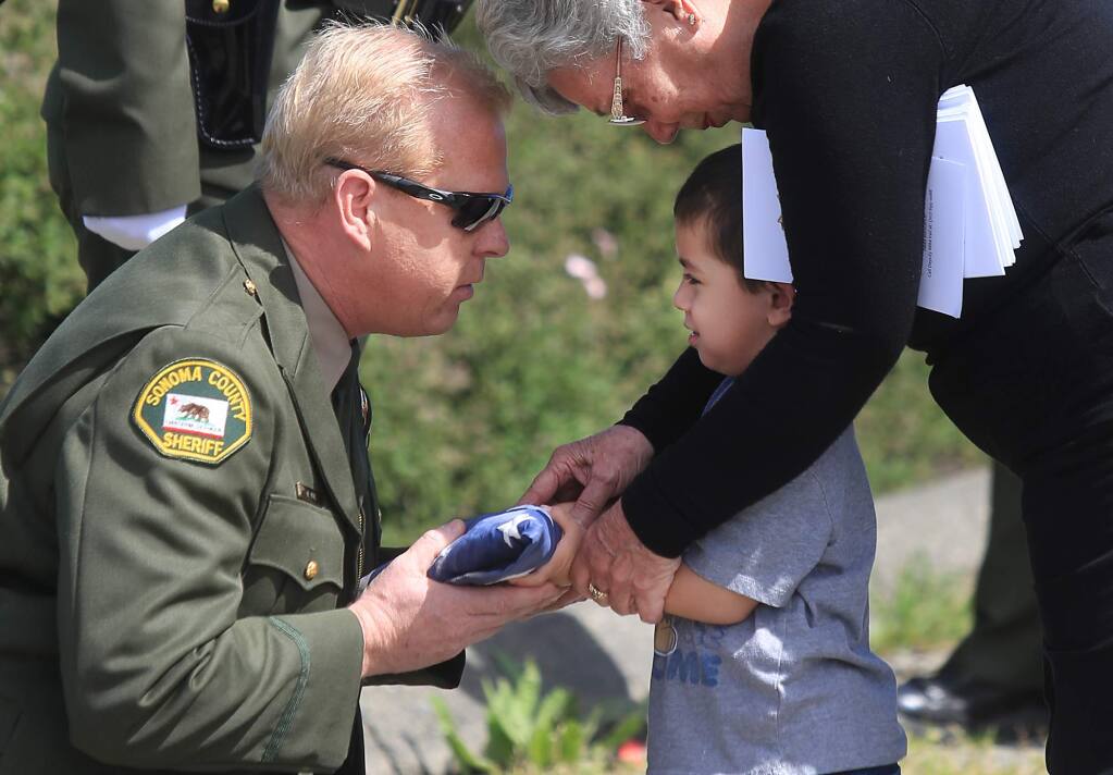Mike Vail, president of the Sonoma County Deputy Sheriff's Association presents an American flag to Barbara Trejo and her great grandson Jordan Bacigalupi, 3, after a ceremony in remembrance for her husband, Sonoma County Sheriff's Deputy Frank Trejo, 58, who was one year away from retirement when he was killed on March 29, 1995 by newly paroled convict Robert Scully. Area law enforcement gathered at the site of Trejo's death to pay their respect, Wednesday March 29, 2017 on Hwy. 12 between Santa Rosa and Sebastopol. Kent Porter / Press Democrat) 2016
