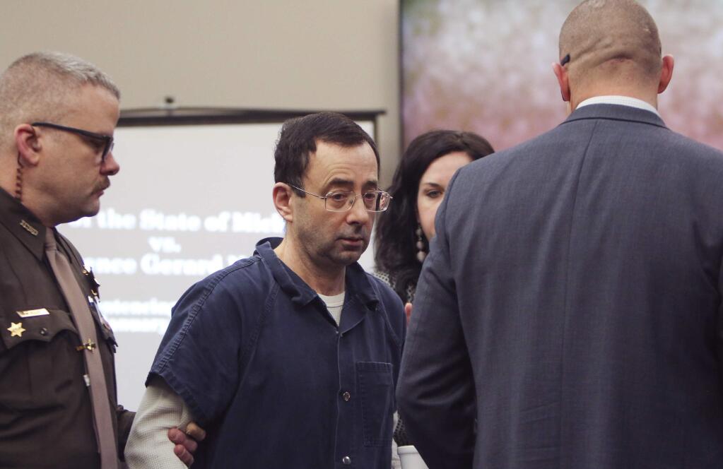 Larry Nassar arrives at court Tuesday, Jan. 16, 2018, for the first day of victim impact statements in Circuit Court Rosemarie Aquilina's courtroom in Lansing, Mich. Flanking Nassar are his attorneys Matt Newburg and Shannon Smith. Nassar pleaded guilty to molesting females with his hands at his Michigan State University office, his home and a Lansing-area gymnastics club. (Matthew Dae Smith/Lansing State Journal via AP)
