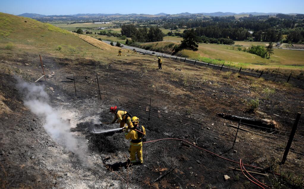 Rancho Adobe Fire District firefighters mop up one of a series of brush fires on the Cotati Grade, Sunday, May 24, 2020, A second alarm was dispatched due to the structure threat caused by the fire. (Kent Porter / The Press Democrat) 2020