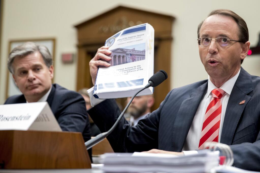 Deputy Attorney General Rod Rosenstein, right, accompanied by FBI Director Christopher Wray, left, holds up an Office of Inspector General's report as he defends himself against questioning by Rep. Jim Jordan, R-Ohio, during a House Judiciary Committee hearing on Capitol Hill in Washington, Thursday, June 28, 2018, on Justice Department and FBI actions around the 2016 presidential election. (AP Photo/Andrew Harnik)