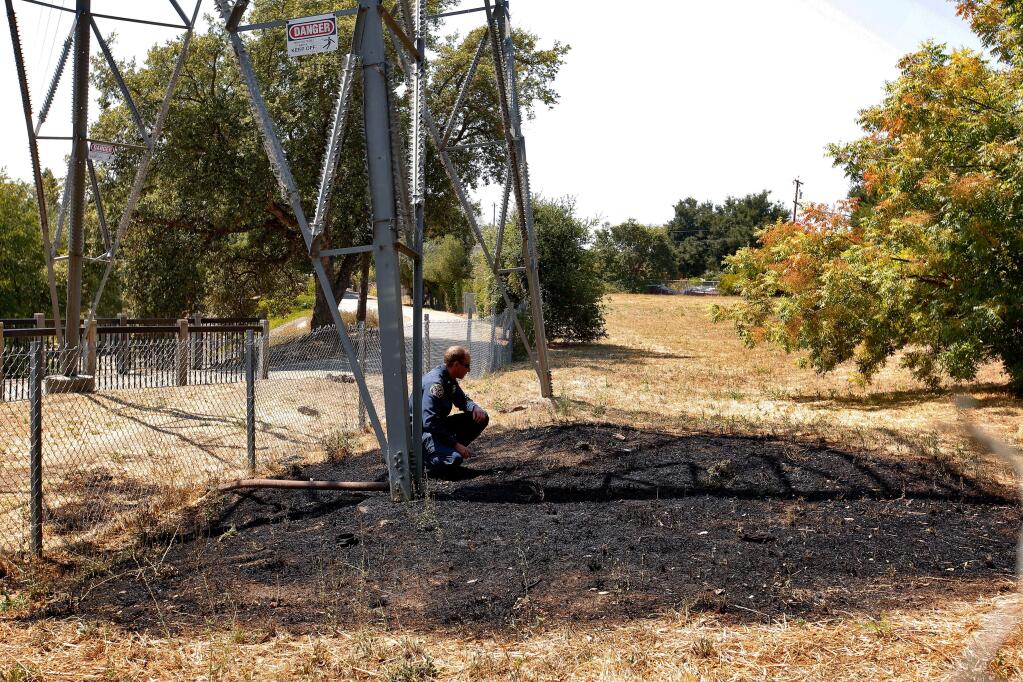 Santa Rosa Assistant Fire Marshal Paul Lowenthal investigates the burned area where a man fell after being shocked as he climbed an electrical transmission tower beside the Santa Rosa Creek Trail near 6th Street in Santa Rosa on Tuesday, Aug. 8, 2017. (ALVIN JORNADA/ PD)