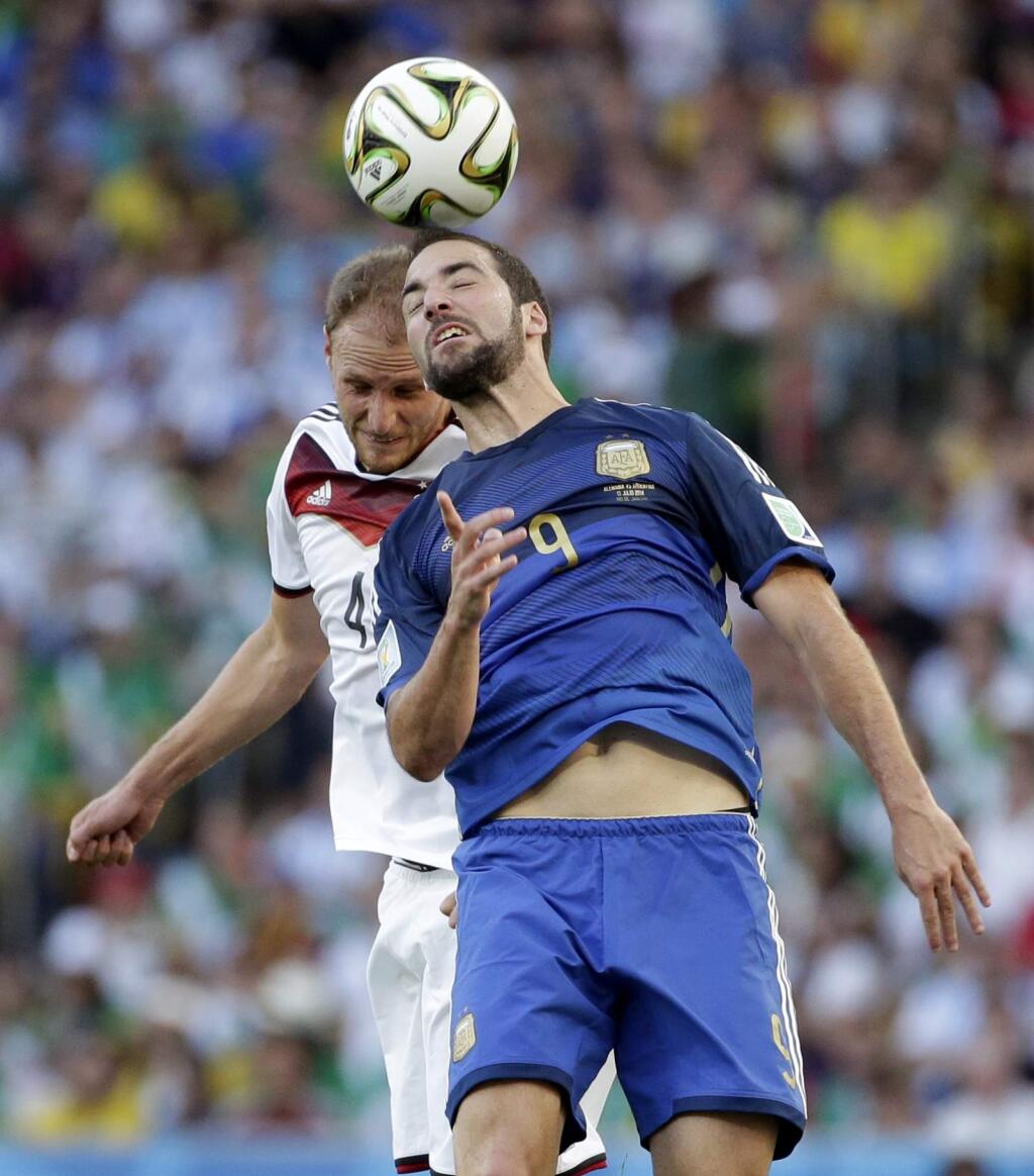 Argentina's Gonzalo Higuain heads the ball away from Germany's Benedikt Hoewedes during the World Cup final soccer match between Germany and Argentina at the Maracana Stadium in Rio de Janeiro, Brazil, Sunday, July 13, 2014. (AP Photo/Felipe Dana)