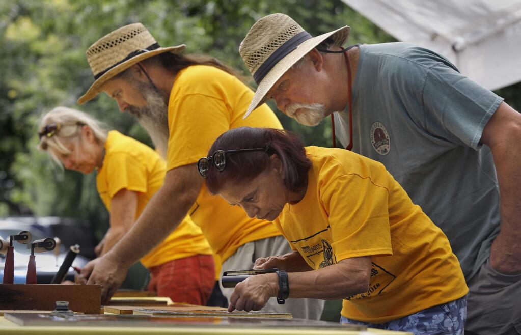 (From front) Volunteers Rakshika Thakor, Tim Haworth, Jim Schafer, and Sally Briggs apply ink to carved print blocks before making prints with an asphalt roller during the Arts and Street Printing Festival at the Sebastopol Center for the Arts on Sunday, July 8, 2018 in Sebastopol, California . (BETH SCHLANKER/The Press Democrat)