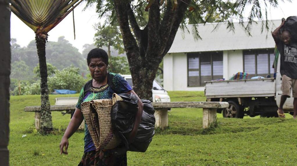 In this photo provided by non-profit organization 350.org, a woman, left, and man gather items in Port Vila, Vanuatu, Saturday, March 14, 2015, in the aftermath of Cyclone Pam. Winds from the extremely powerful cyclone that blew through the Pacific's Vanuatu archipelago are beginning to subside, revealing widespread destruction. (AP Photo/350.org, Isso Nihemi ) EDITORIAL USE ONLY, NO SALES
