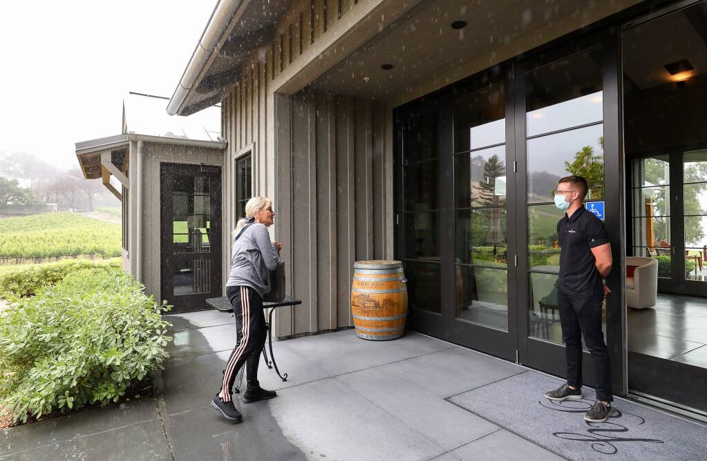 Wine club member Debra Kazarian picks up her wine curbside at the Robert Young Estate Winery tasting room, while greeted by Robert Young II, near Geyserville on Monday, May 11, 2020. (Christopher Chung/ The Press Democrat)