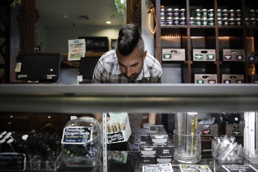 FILE - In this June 27, 2017, file photo, Jerred Kiloh, owner of the licensed medical marijuana dispensary Higher Path, stocks shelves with with cannabis products in Los Angeles. Weedmaps a major online pot shop directory and cannabis marketplace announced Wednesday, Aug. 21, 2019, that it will no longer allow black-market businesses to advertise on its site, a decision that could boost California's efforts to rein in its vast illegal market. Kiloh, who heads the United Cannabis Business Association, an industry group, projected that half of California's illegal operations could dry up once they are denied access to Weedmaps ads. (AP Photo/Jae C. Hong, File)