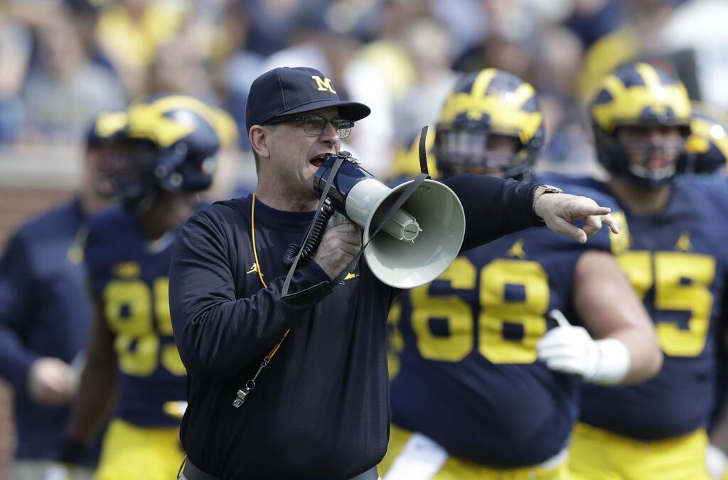 In this April 15, 2017, file photo, Michigan head coach Jim Harbaugh talks to his players during the team's spring game, in Ann Arbor, Mich. The increasing visibility of spring football games has offered plenty of feel-good moments and fan-friendly opportunities. What they don't provide is much insight into what these teams will be doing this fall. With so many spring games on television, teams don't want to give anything away to rival coaches who may be tuning in. (AP Photo/Carlos Osorio, File)