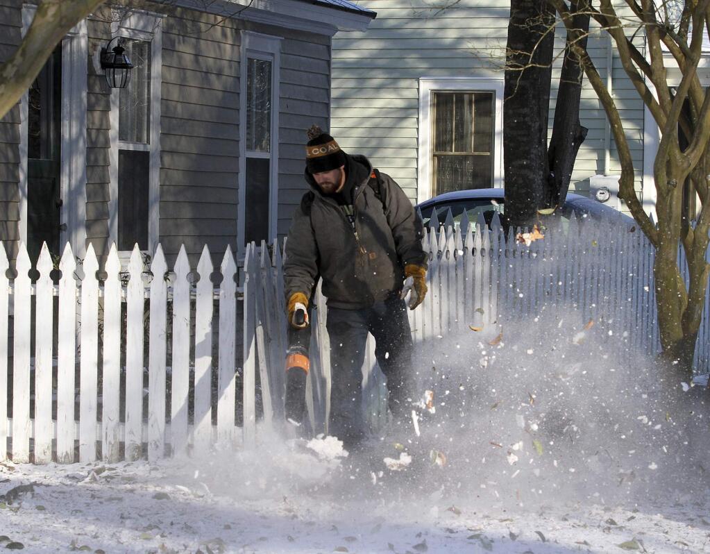 Spencer Avolis, of Avolis Land Works, clears snow from a sidewalk and residence along Bern Street in New Bern, N.C., Thursday, Jan. 18, 2018, after a brief winter front brought snow and frigid weather across the region overnight. (Gray Whitley/Sun Journal via AP)