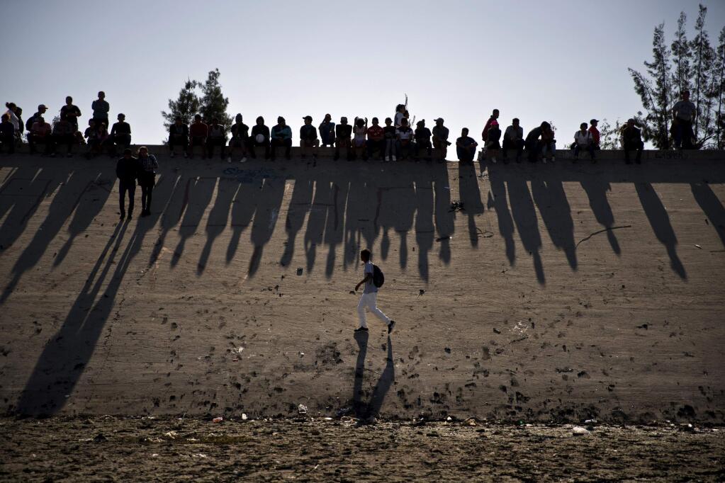 Migrants near the Chaparral border crossing watch clashes with U.S. border agents on Feb. 25. A San Diego TV station reported that the U.S. government ran an operation to screen journalists, activists and others while investigating last year's migrant caravan from Mexico. (RAMON ESPINOSA / Associated Press)