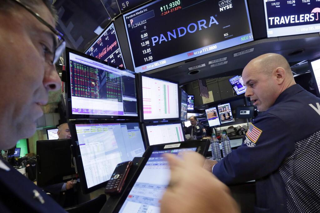 FILE - In this Oct. 23, 2015 file photo, Specialist Mark Fitzgerald, right, works at the post on the floor of the New York Stock Exchange that trades Pandora. Pandora says it has revamped its $5 a month Internet radio service, Thursday, Sept. 15, 2016, giving listeners the ability to skip and replay more songs. (AP Photo/Richard Drew)