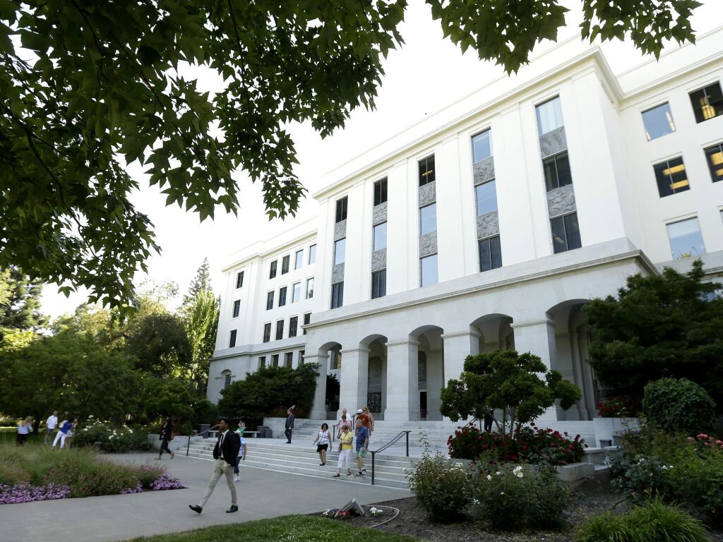 FILE - In this June 14, 2018, file photo, people leave the office building attached to the state Capitol in Sacramento, Calif. A new report on Tuesday, July 16, 2019, by California's state auditor is raising concerns about information security at government agencies that do not fall under the standards of the state's department of technology. (AP Photo/Rich Pedroncelli, File)