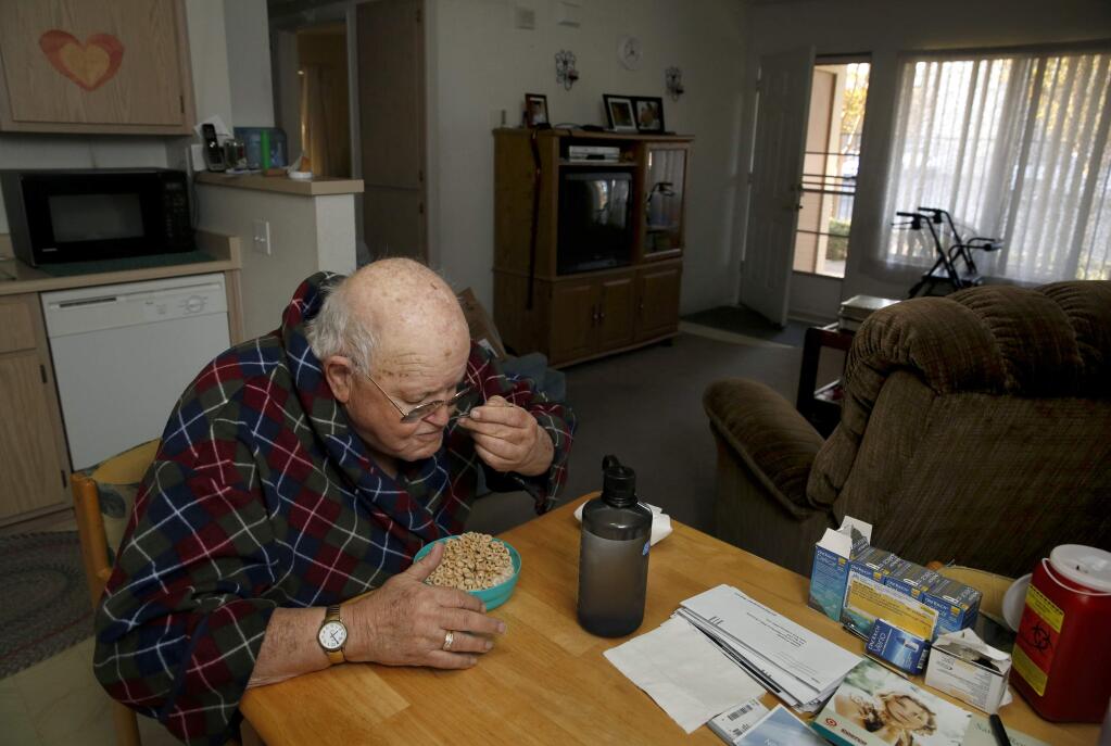 Wayne Martinez eats his breakfast at his kitchen table where a stack of unpaid bills sits at the Vintage Park Senior Apartments in Santa Rosa, on Thursday, March 26, 2015. (BETH SCHLANKER/ The Press Democrat)