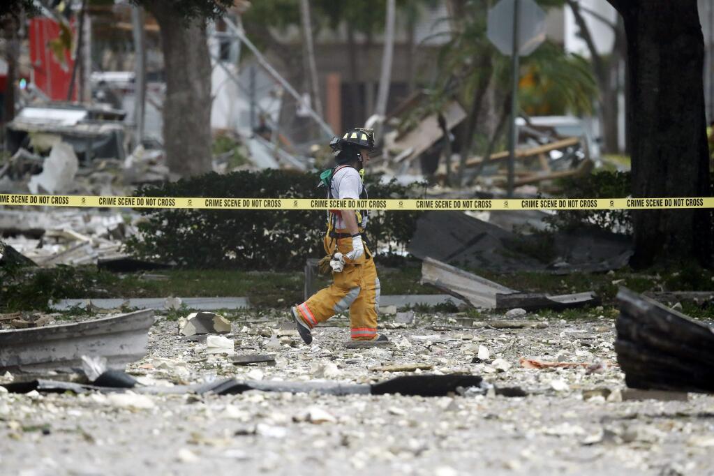 A firefighter walks through the remains of a building after an explosion on Saturday, July 6, 2019, in Plantation, Fla. Several people were injured after a vacant pizza restaurant exploded in the South Florida shopping plaza Saturday, according to police. The restaurant was destroyed, and nearby businesses were damaged. (AP Photo/Brynn Anderson)