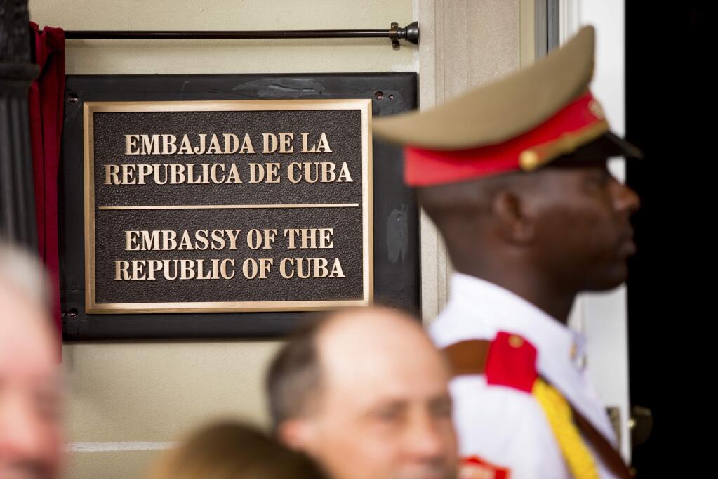 FILE - In this july 20, 2015 file photo, a member of the Cuban honor guard stands next to a new plaque at the front door of the newly reopened Cuban embassy in Washington. The State Department has expelled two diplomats from Cuba's Embassy in Washington following a series of unexplained incidents in Cuba that left U.S. officials there with physical symptoms. (AP Photo/Andrew Harnik, File, Pool)