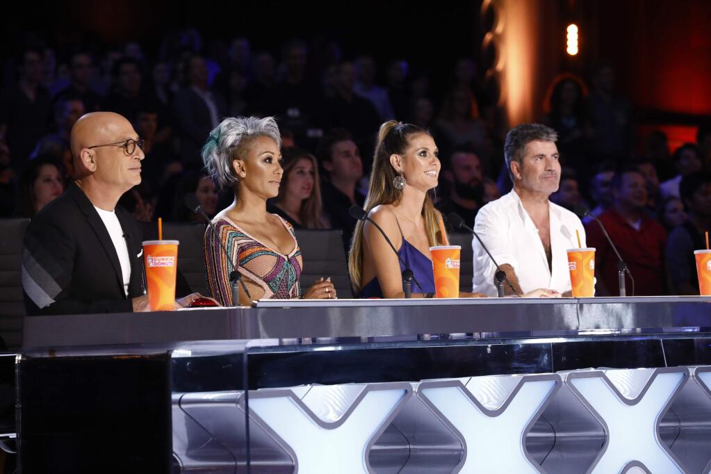 In this Tuesday, Aug. 22, 2017 photo provided by NBC, judges Howie Mandel, Mel B, Heidi Klum and Simon Cowell participate in a live broadcast of 'America's Got Talent' in Los Angeles. Mel B threw a cup of water on Cowell and walked off the stage after Cowell made a joke about her wedding night during the show. (Trae Patton/NBC via AP)