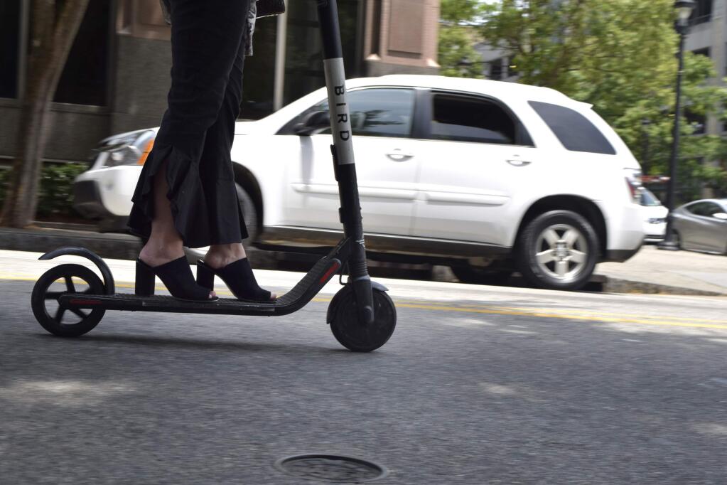 In this May 28, 2019, photo, a woman rides an electronic scooter in downtown Raleigh, N.C. As electric scooters have rolled into more than 100 cities worldwide, many of the people riding them have ended up in the emergency room with serious injuries. Others have been killed. (AP Photo/Amanda Morris)