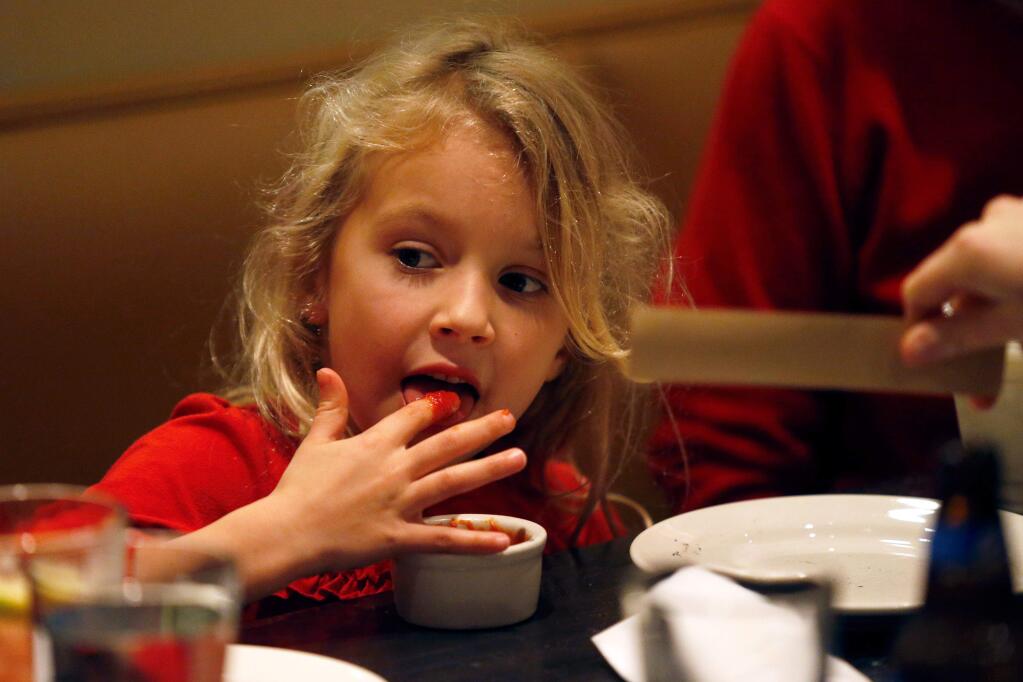 Six-year-old Dottie Palmer licks pizza sauce off her finger while having dinner with her family at Rosso Pizzeria and Wine Bar in Santa Rosa, California on Saturday, December 10, 2016. (Alvin Jornada / The Press Democrat)
