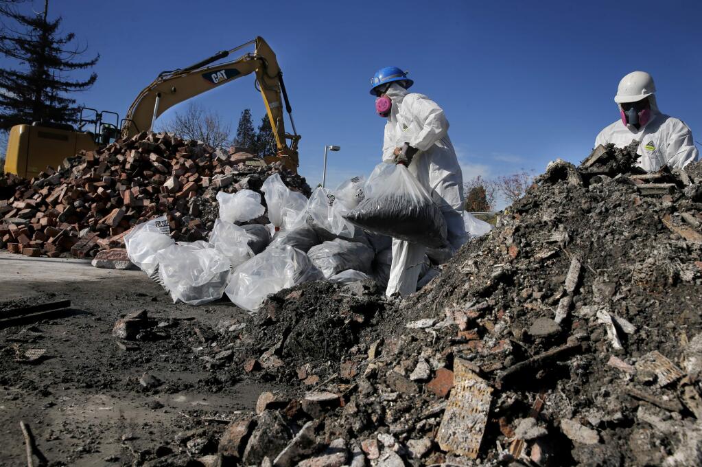 Christian Velazquez, left, and Saul Campos, employees of Excel Site Services, bag up burned debris for disposal at Mountain Mike's Pizza on Cleveland Avenue on Wednesday, Nov. 29, 2017 in Santa Rosa. (BETH SCHLANKER/ PD)