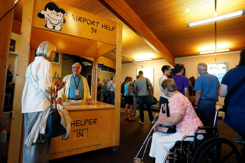 Airport volunteer Ken Hicks, second from left, answers questions for travelers at Charles M. Schulz-Sonoma County Airport in Santa Rosa, California, on Tuesday, July 11, 2017. Airport officials are planning to double the size of Gate 2, add more parking spaces and build a new 28,000 square foot terminal in the future. (Alvin Jornada / The Press Democrat)