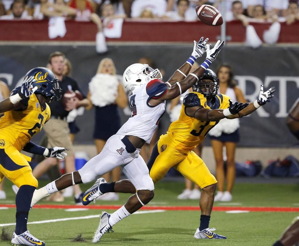 Arizona running back Davonte' Neal (19) and California cornerback Cedric Dozier (37) reach for a pass during the first half of an NCAA college football game, Saturday, Sept. 20, 2014, in Tucson, Ariz. (AP Photo/Rick Scuteri)