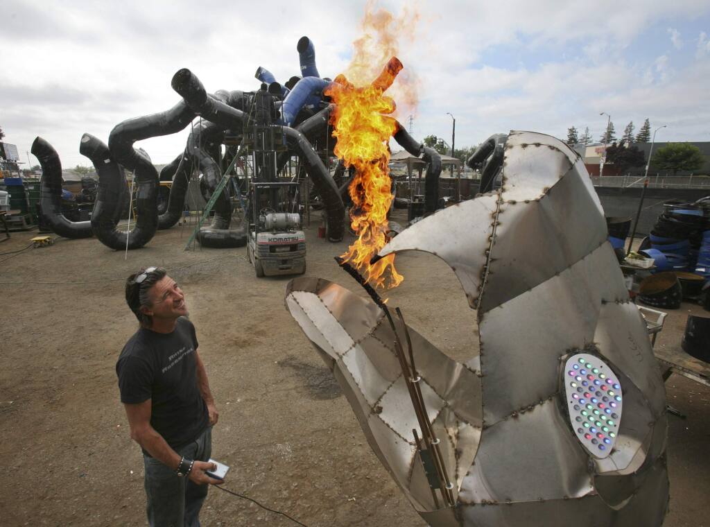 Kevin Clark tests one of the flame throwing fire-breathing snake heads for his giant fire-breathing Medusa seen in the background that he is building for this years Burning Man at his shop in Petaluma on Saturday August 1, 2015.(SCOTT MANCHESTER/ARGUS-COURIER STAFF)