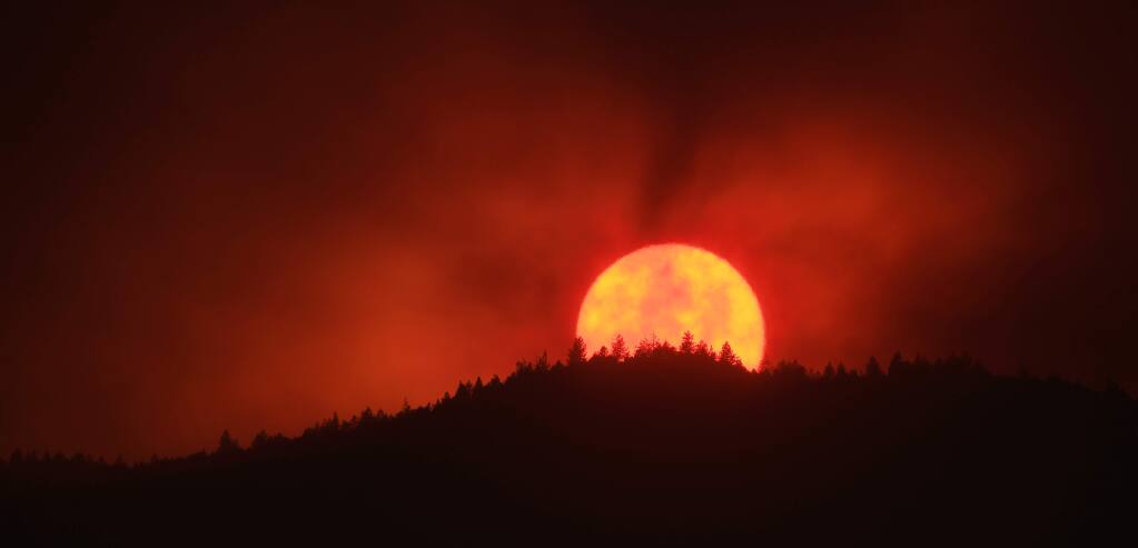 Thick smoke from the Kincade fire obscures the setting sun as seen from the Middletown side of the Mayacamas Mountains, Friday, Oct. 25, 2019. (Kent Porter / The Press Democrat) 2019
