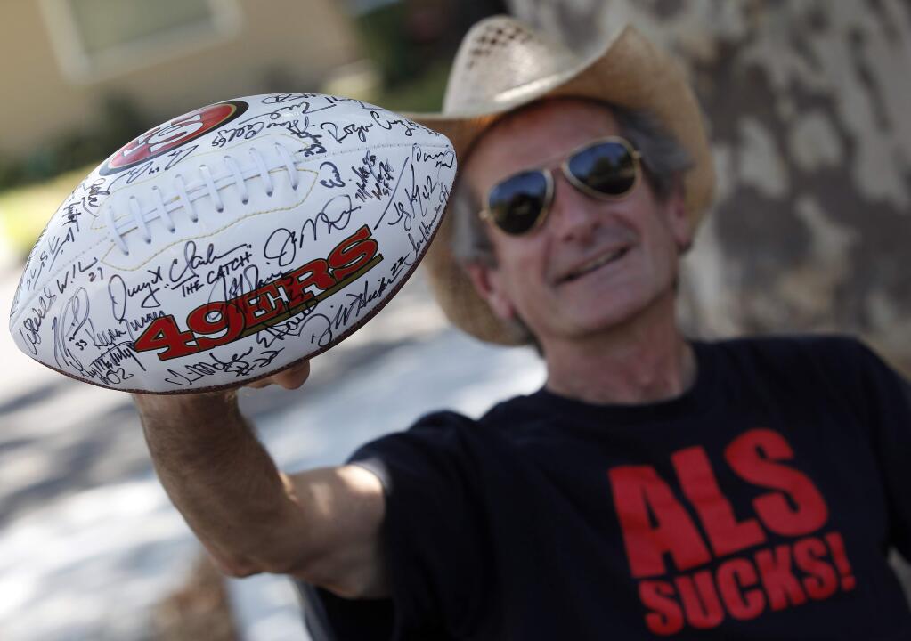 Paul Stimson, who was diagnosed with ALS, holds a football donated for the 10th Annual Napa Valley Ride to Defeat ALS auction. Stimson's friend Blake Ridgway mentioned to his coworker, Eric Wright, former 49ers player, the fundraiser. Wright was able to get a football signed by football players during the 'Legends of Candlestick,' game to donate to the cause. (Crista Jeremiason / The Press Democrat)