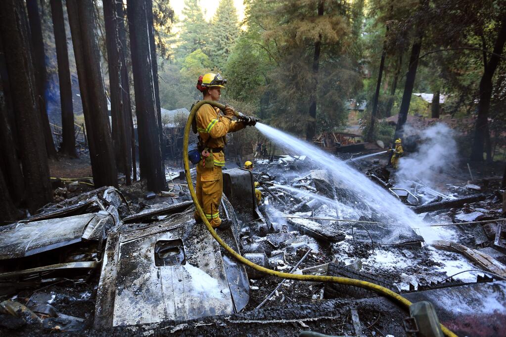 Cal Fire firefighters douse hot spots on a large structure fire that threatened several homes in Forestville's Summerhome Park community, Monday Sept. 1, 2014. (Kent Porter / Press Democrat) 2014