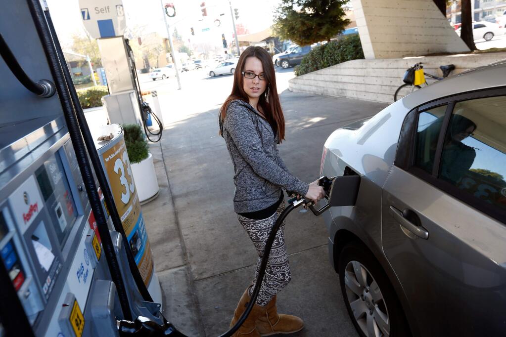 FILE - Ashley Bott of Santa Rosa watches the gas pump meter as she fills her tank at the Chevron on the corner of Mendocino Avenue and College Avenue in Santa Rosa, California on Thursday, December 31, 2015. (Alvin Jornada / The Press Democrat)
