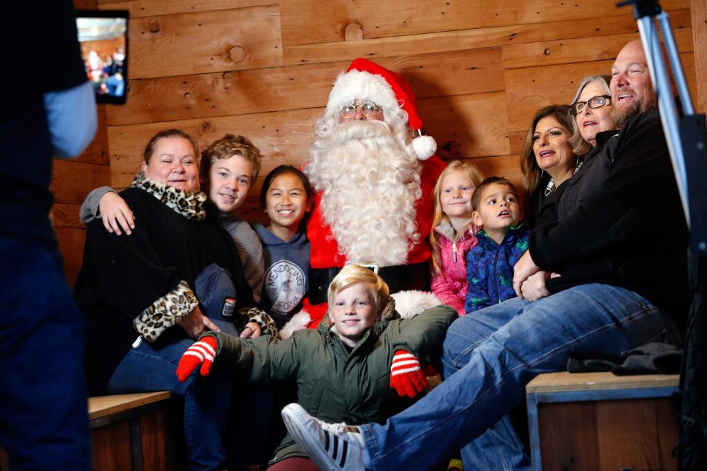 The Rahmn and Pruess families have the photo taken with Santa Claus during Winter Lights at Old Courthouse Square in Santa Rosa, California, on Friday, November 23, 2018. (Alvin Jornada / The Press Democrat)