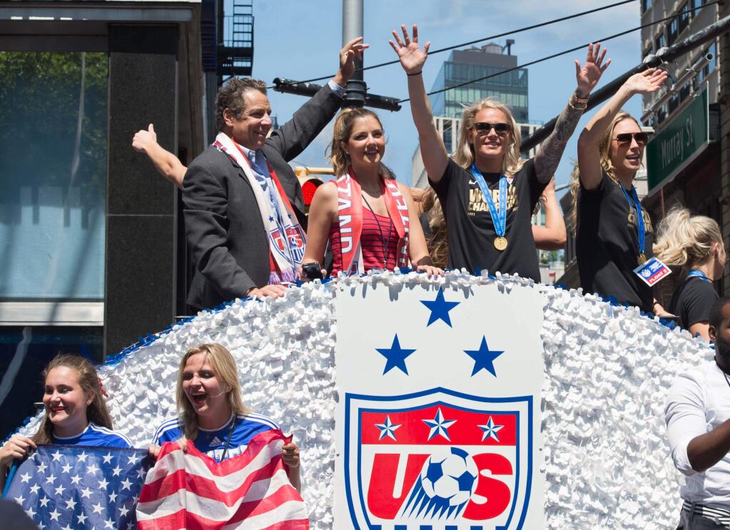 U.S. women's soccer team members are joined by New York Gov. Andrew Cuomo, left, as their float makes its way up Broadway's Canyon of Heroes during the ticker tape parade to celebrate the team's World Cup victory, Friday, July 10, 2015, in New York. (AP Photo/Bryan R. Smith)